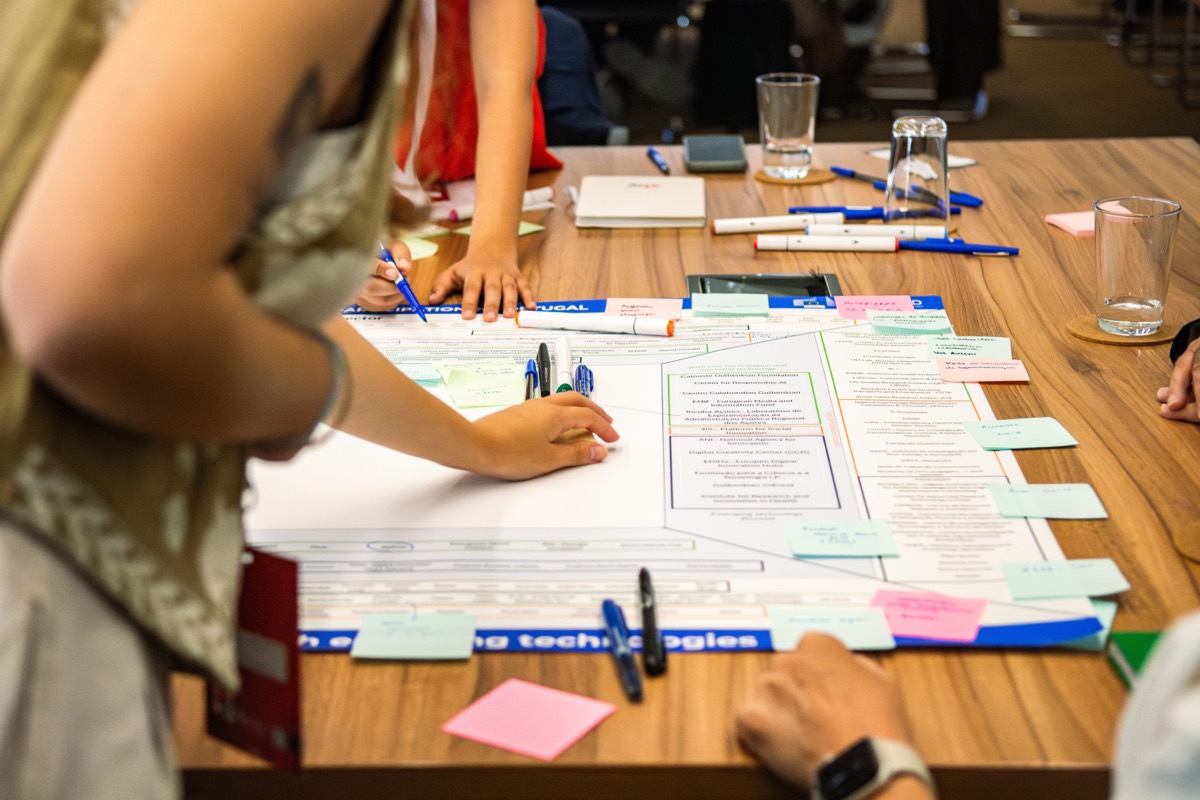 Workshop participants collaborating around a table covered in printed materials